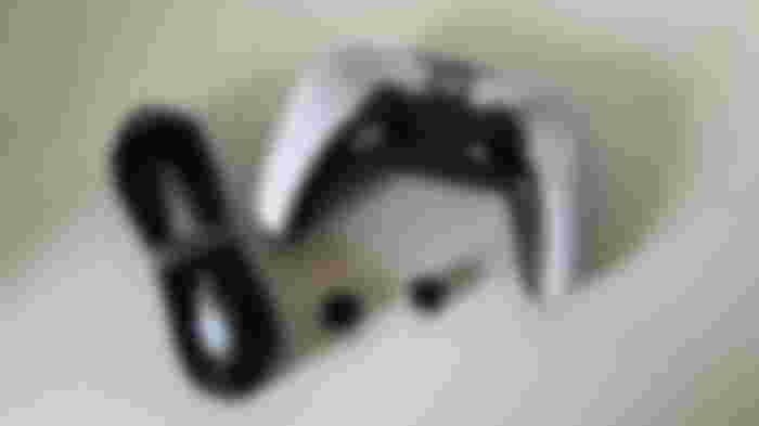 White and black Xbox-branded controller next to a black USB cable and two separate black thumbsticks.