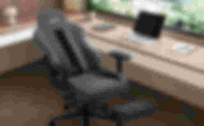 Grey reclined office chair in front of a brown desk.
